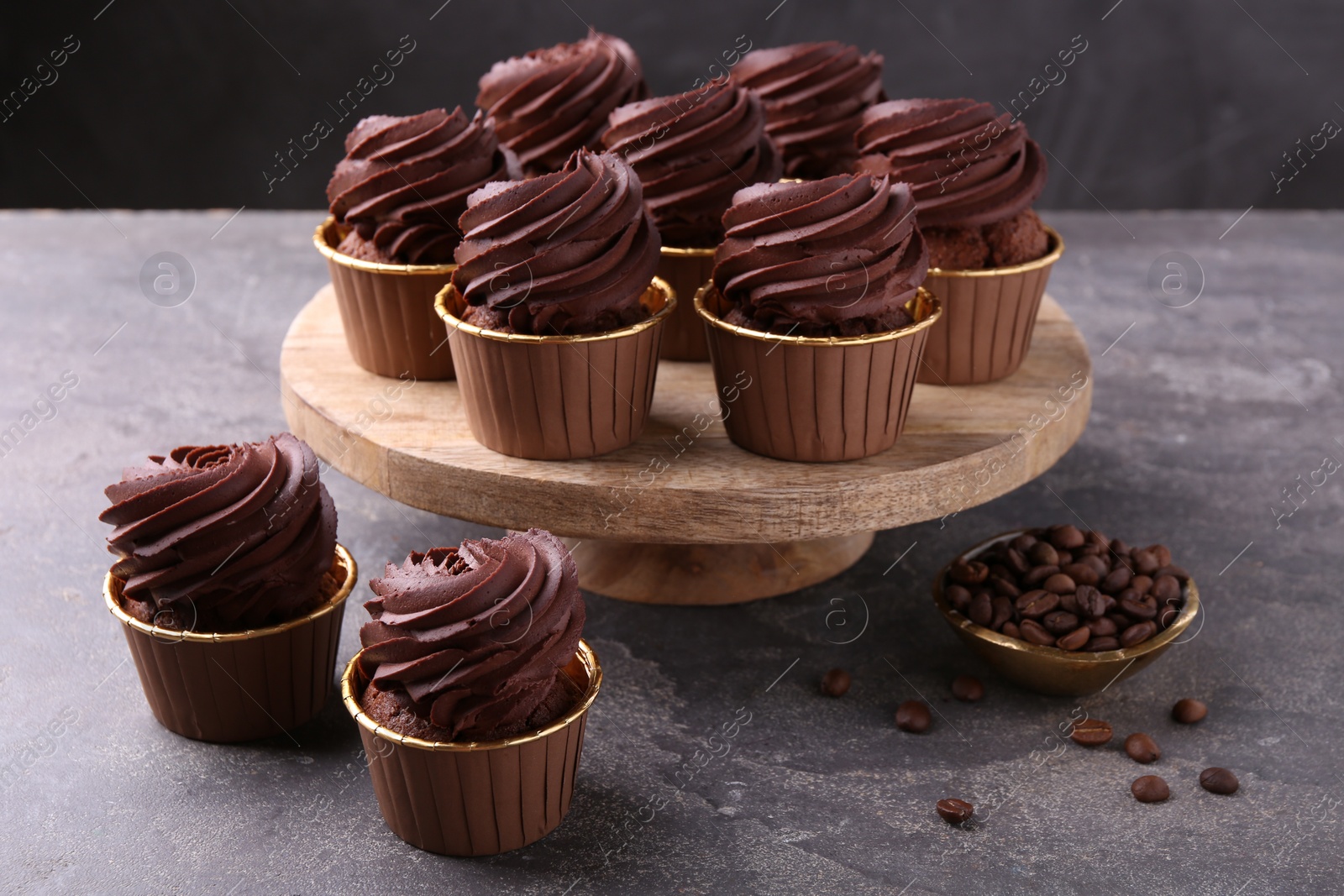 Photo of Delicious chocolate cupcakes and coffee beans on grey textured table