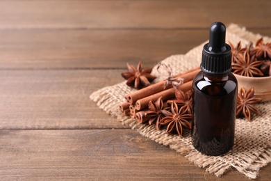 Photo of Anise essential oil and spices on wooden table, space for text