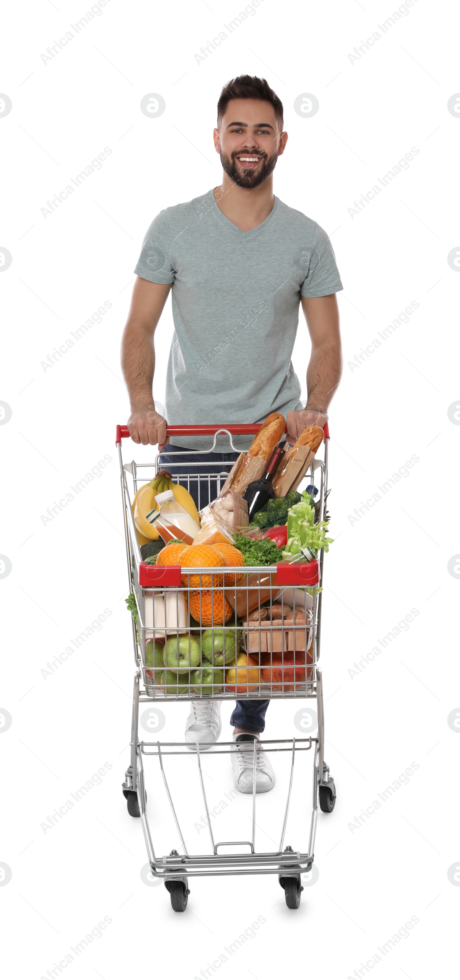 Photo of Happy man with shopping cart full of groceries on white background