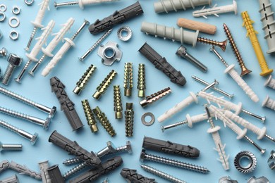 Many different fasteners and dowels on light blue background, flat lay