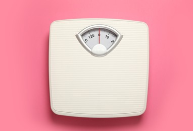 Weigh scales on pink background, top view. Overweight concept