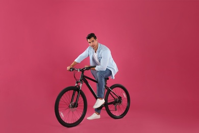 Photo of Handsome young man with modern bicycle on pink background