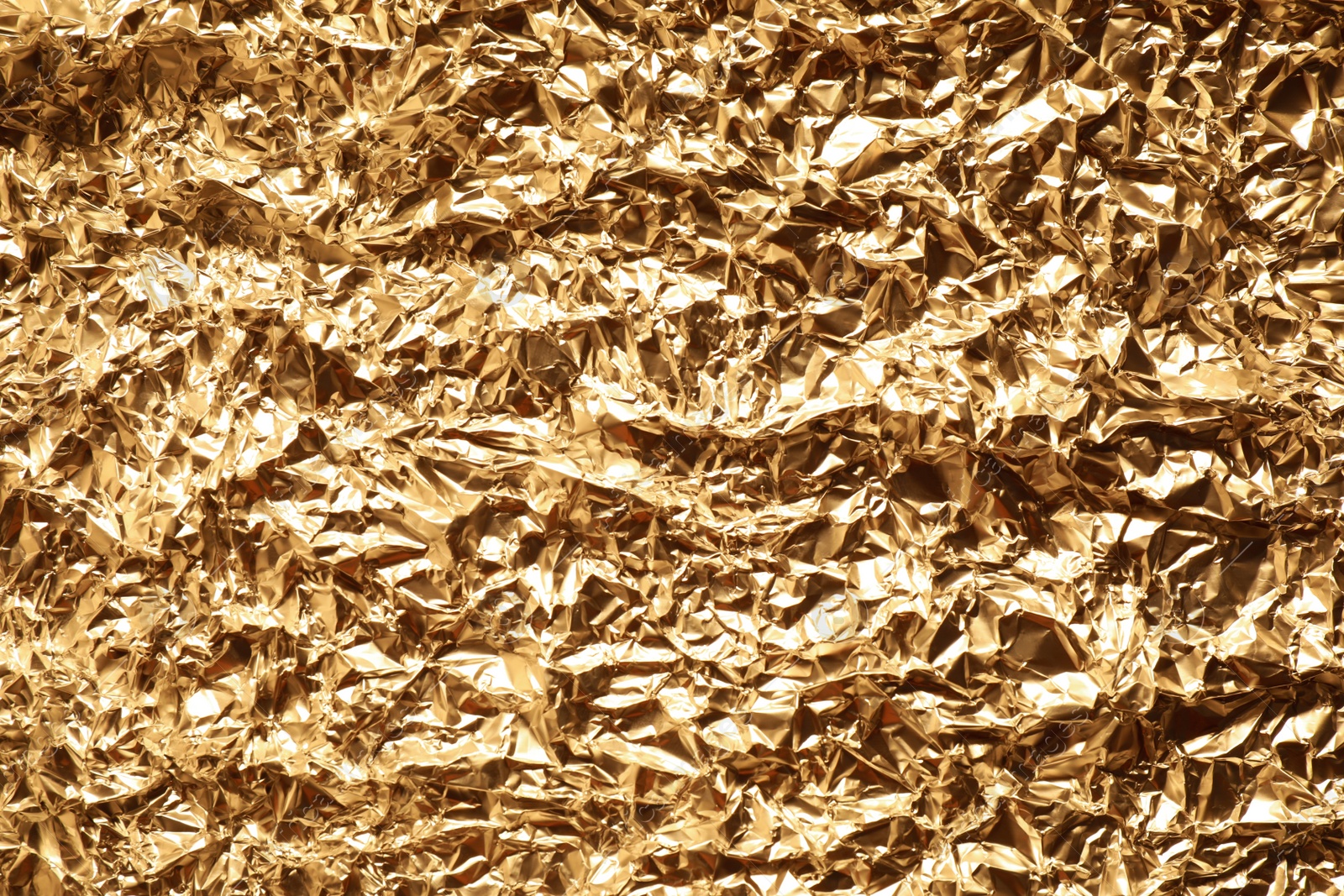 Photo of Crumpled gold foil as background, top view