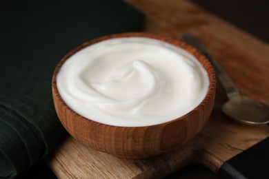 Photo of Delicious natural yogurt in bowl and spoon on table, closeup