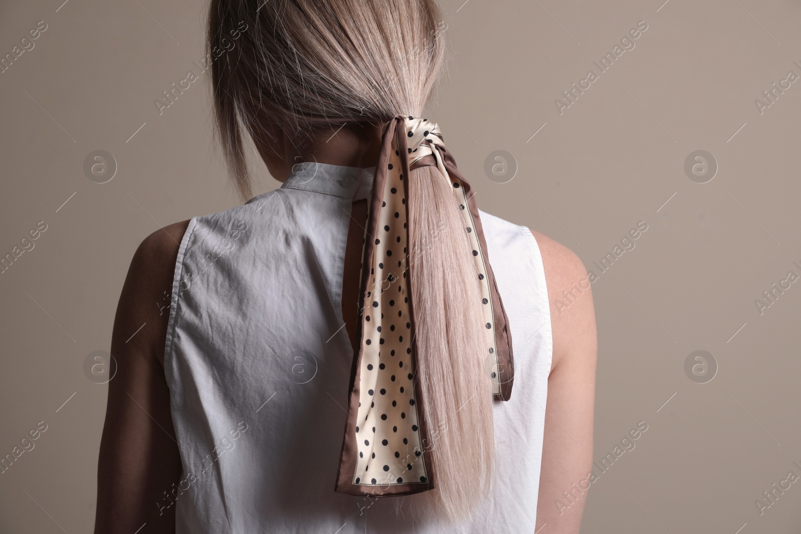 Photo of Young woman with stylish bandana on beige background, back view