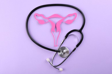 Photo of Reproductive medicine. Paper uterus and stethoscope on violet background, top view