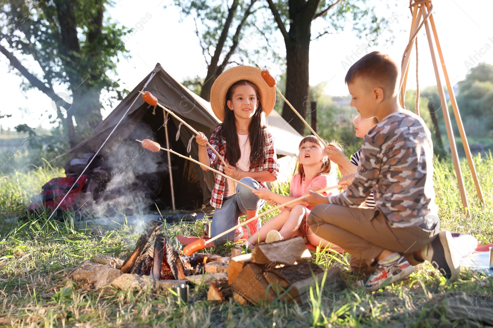 Photo of Little children frying sausages on bonfire. Summer camp