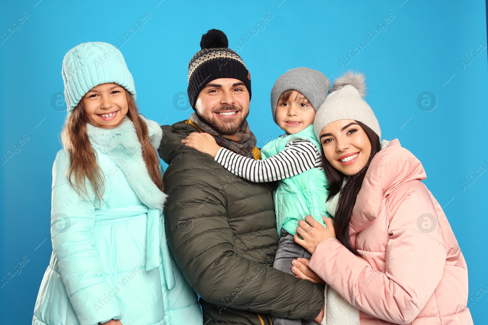 Photo of Happy family in warm clothes on blue background. Winter vacation