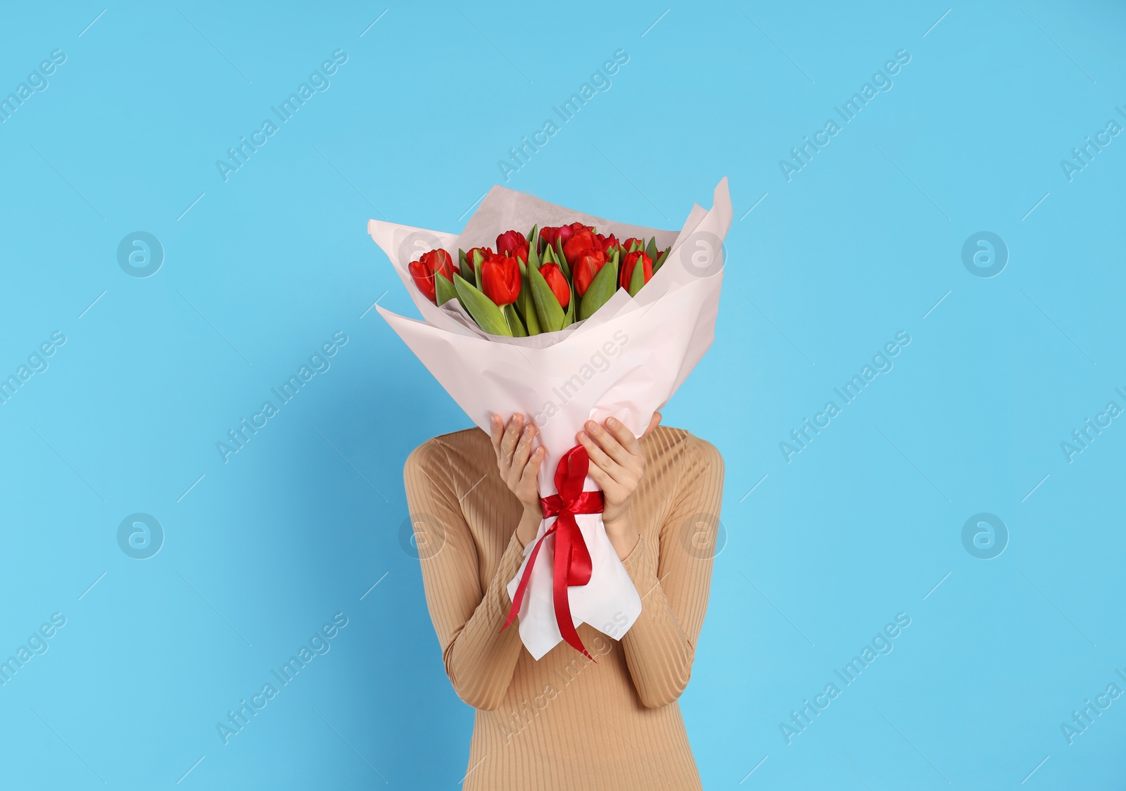 Photo of Woman with red tulip bouquet on light blue background. 8th of March celebration