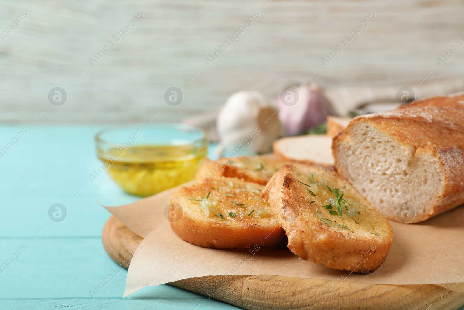 Photo of Slices of toasted bread with garlic and herbs on light blue wooden table