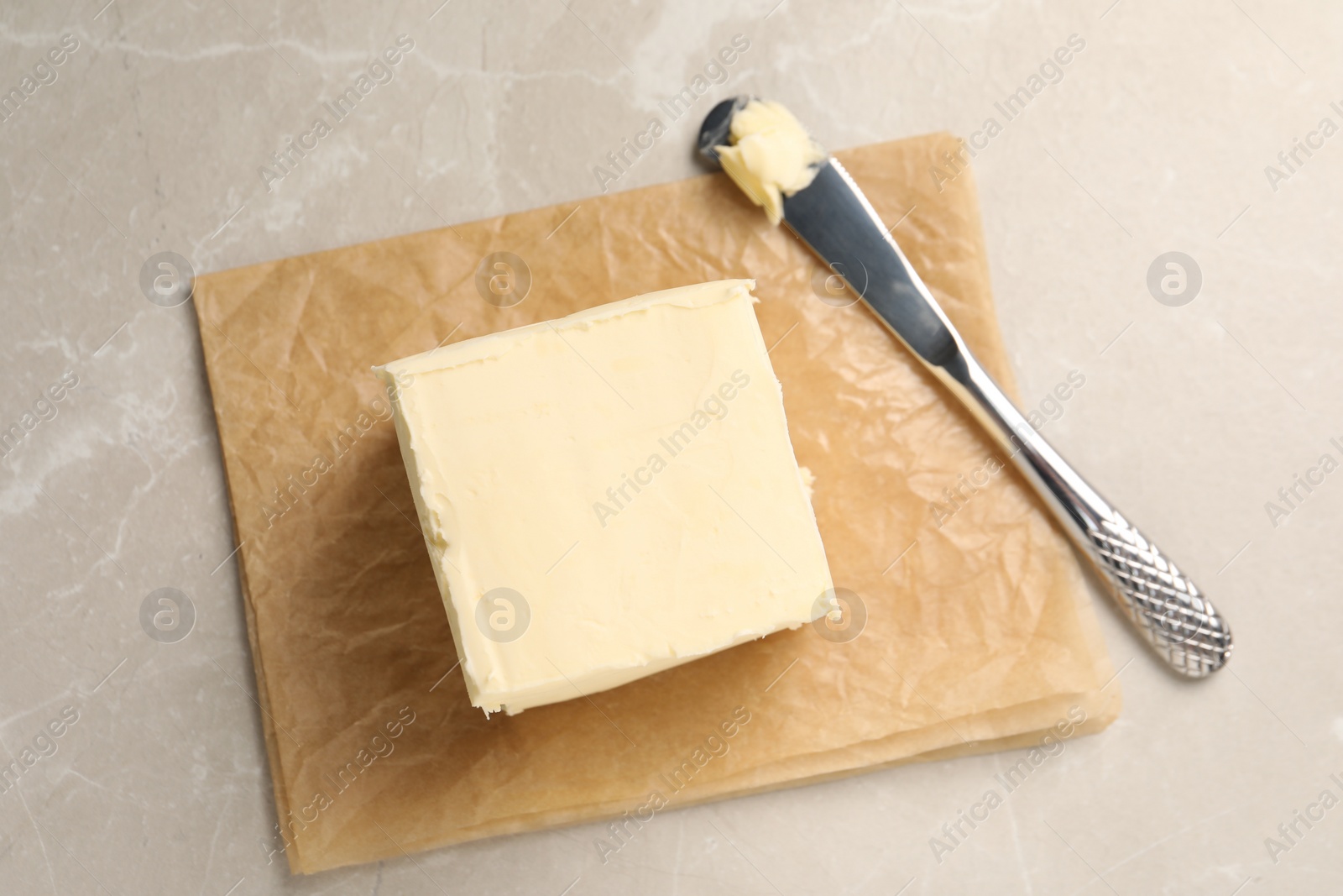 Photo of Block of tasty butter and knife on light table, top view