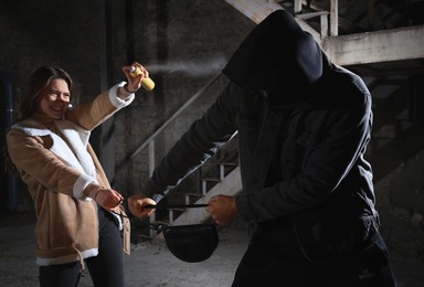 Photo of Woman using pepper spray while thief trying to steal her bag outdoors at night. Self defense concept