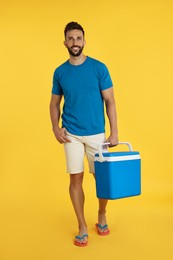 Photo of Happy man with cool box on yellow background