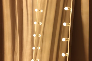 Photo of Modern mirror with light bulbs in makeup room, closeup