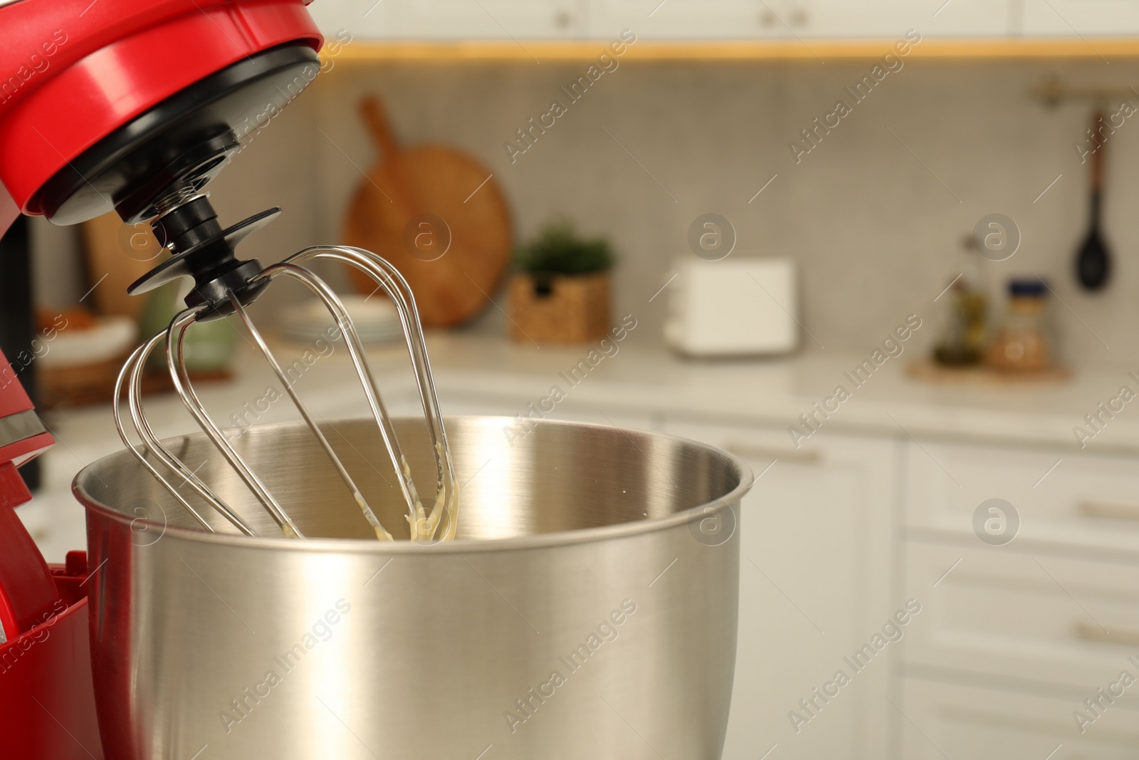 Photo of Modern red stand mixer with cream in kitchen, closeup. Space for text