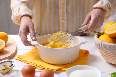 Woman cooking lemon curd at white wooden table, closeup