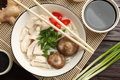 Photo of Delicious ramen with meat and ingredients on wooden table, flat lay. Noodle soup