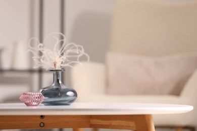 Photo of Vase with dried plant and candle on white table in living room, space for text
