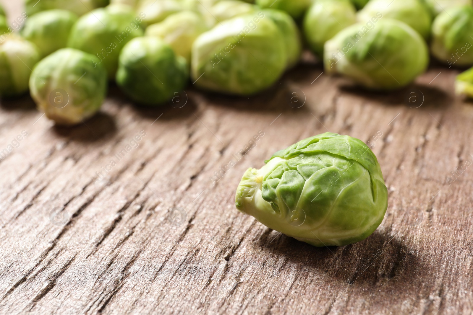 Photo of Fresh Brussels sprouts on wooden table, closeup. Space for text