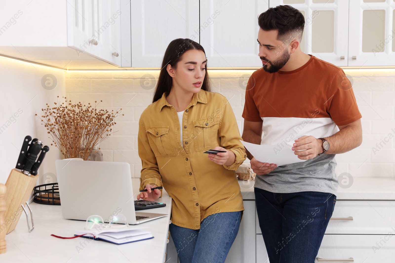 Photo of Young couple discussing family budget in kitchen