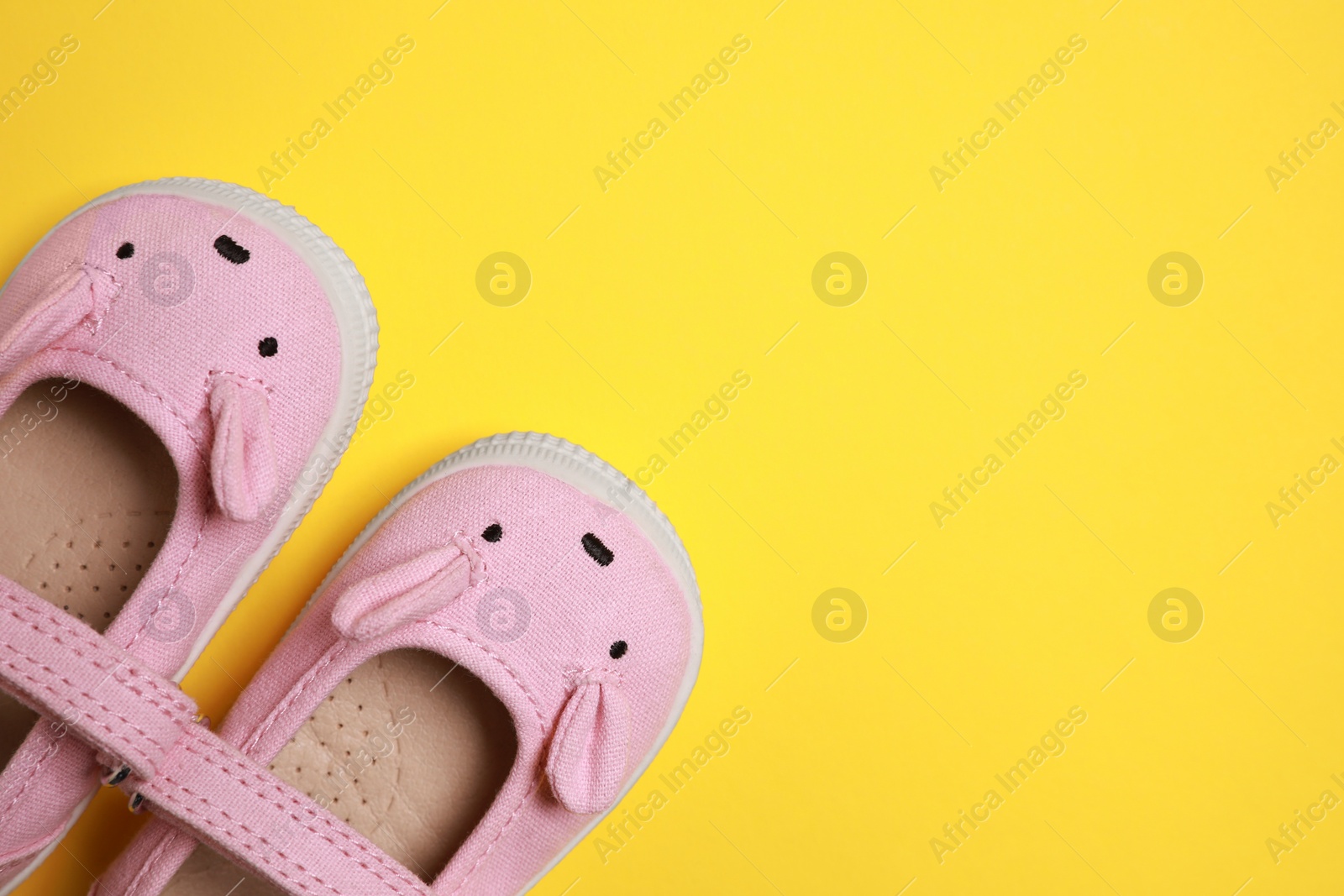 Photo of Cute baby shoes on yellow background, flat lay. Space for text