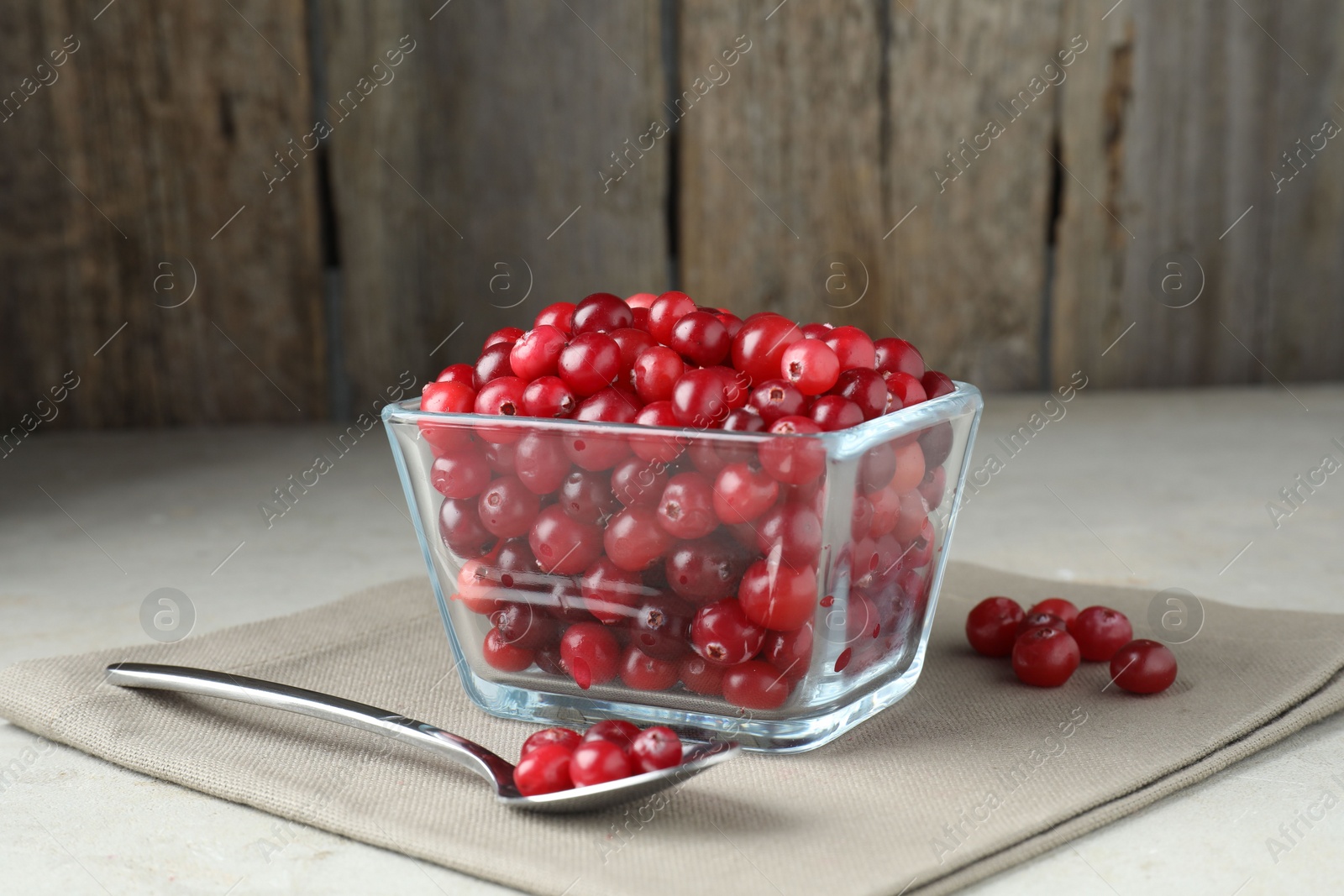 Photo of Cranberries in bowl and spoon on light grey table