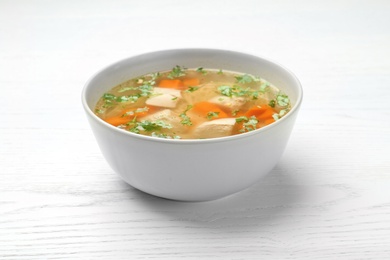 Photo of Bowl with fresh homemade chicken soup on wooden table