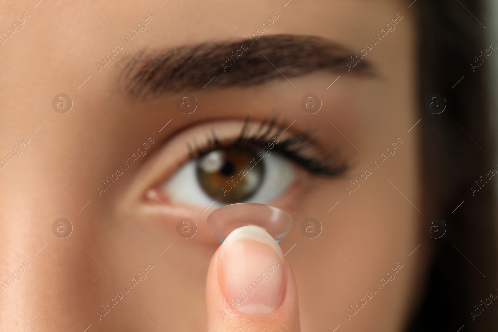 Photo of Woman putting contact lens in her eye, closeup view