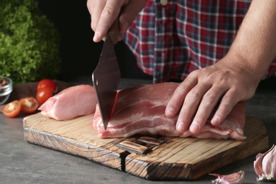 Photo of Man cutting fresh raw meat on table, closeup