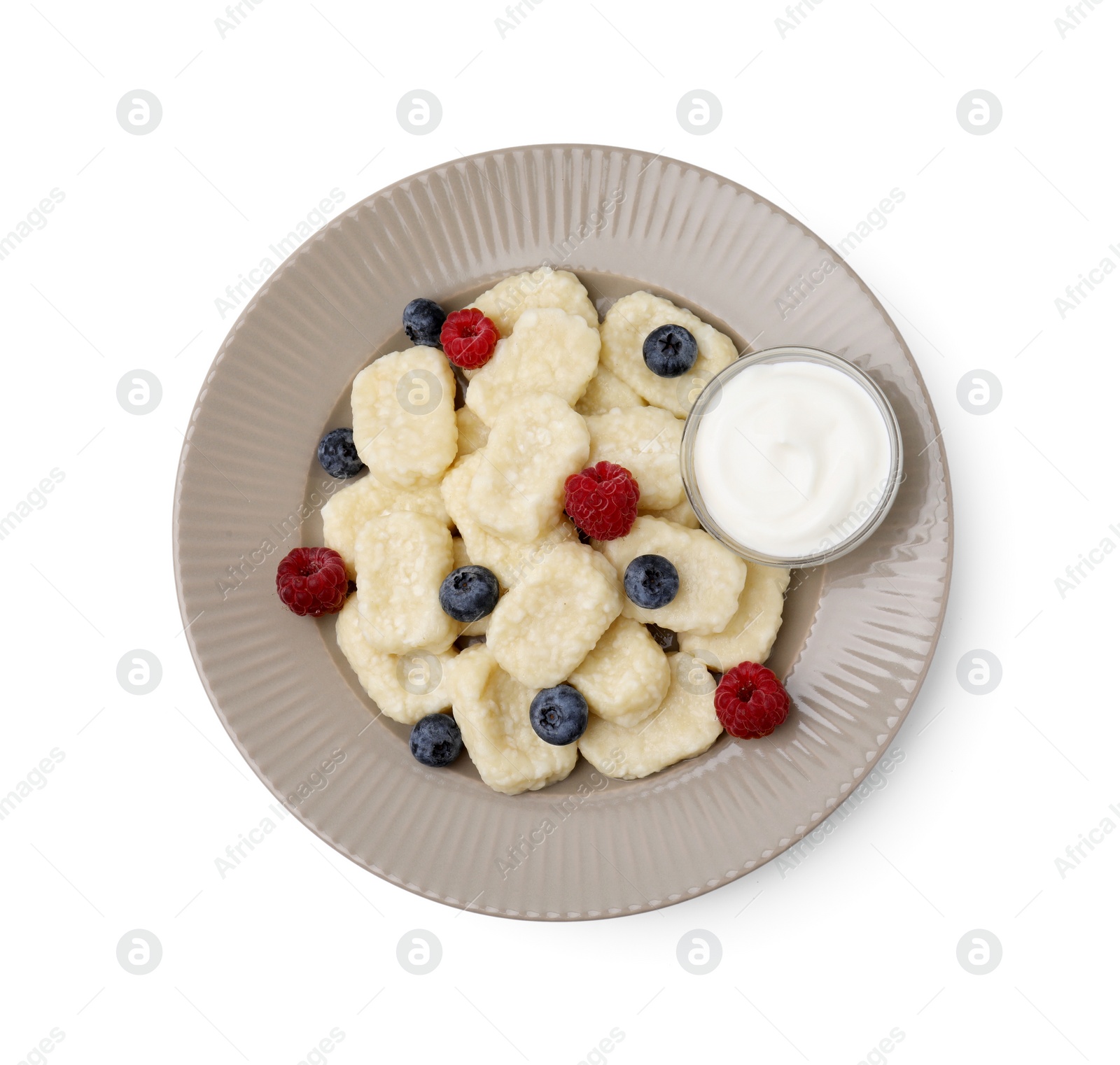 Photo of Plate of tasty lazy dumplings with berries and sour cream isolated on white, top view