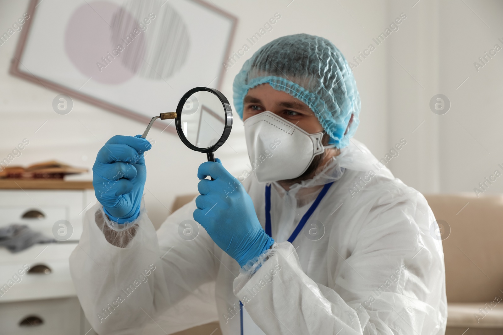 Photo of Investigator in protective suit examining evidence at crime scene indoors