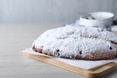 Photo of Delicious Stollen sprinkled with powdered sugar on wooden table. Space for text