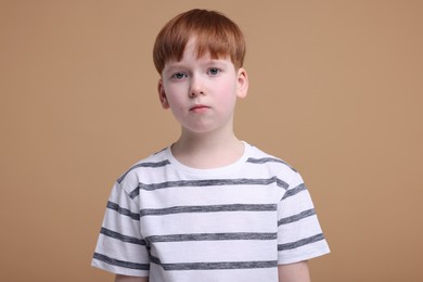 Photo of Portrait of sad little boy on beige background