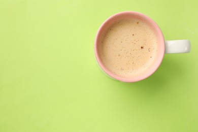 Photo of Aromatic coffee in cup on light green background, top view. Space for text