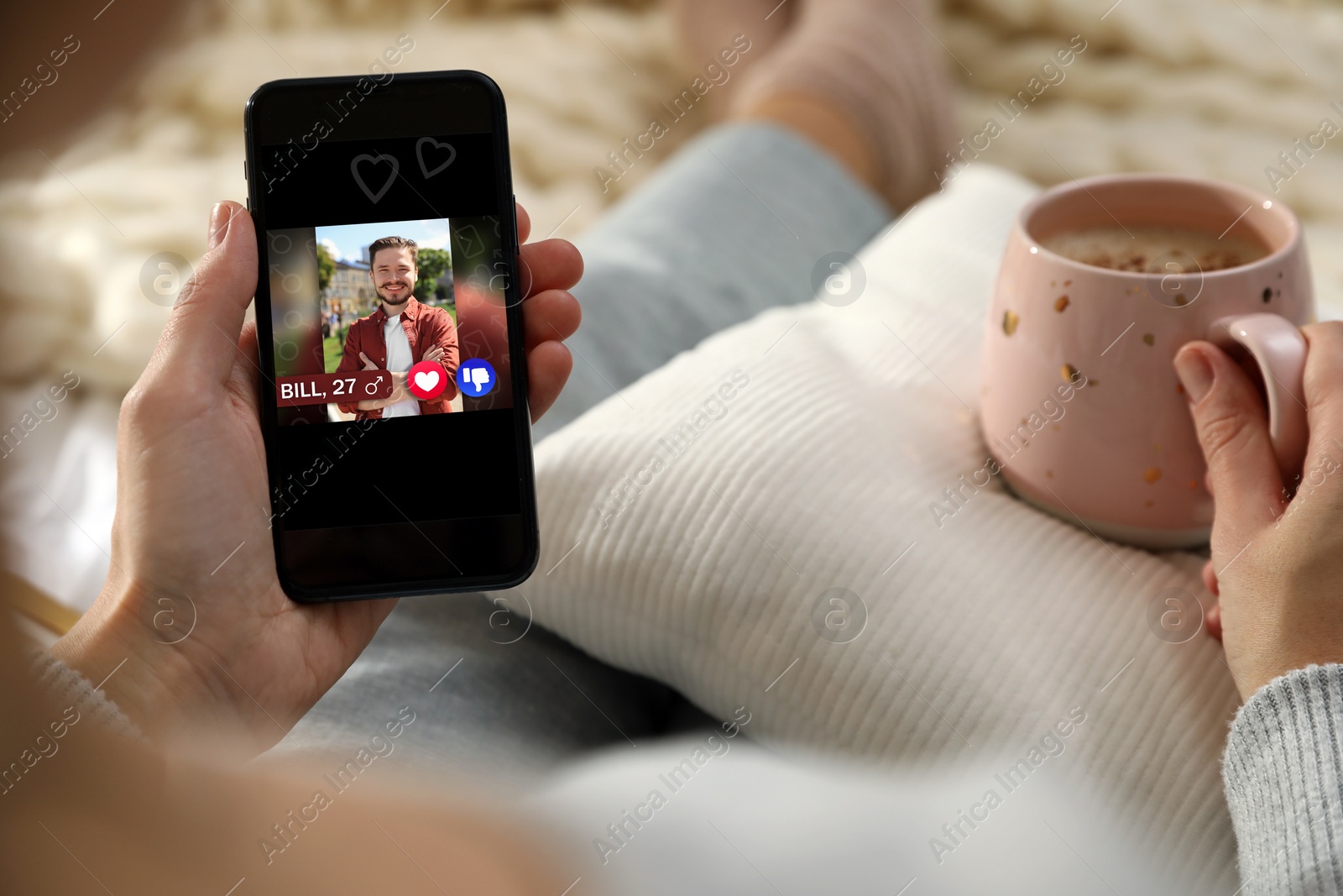 Image of Woman viewing male profile on dating site via mobile phone at home, closeup