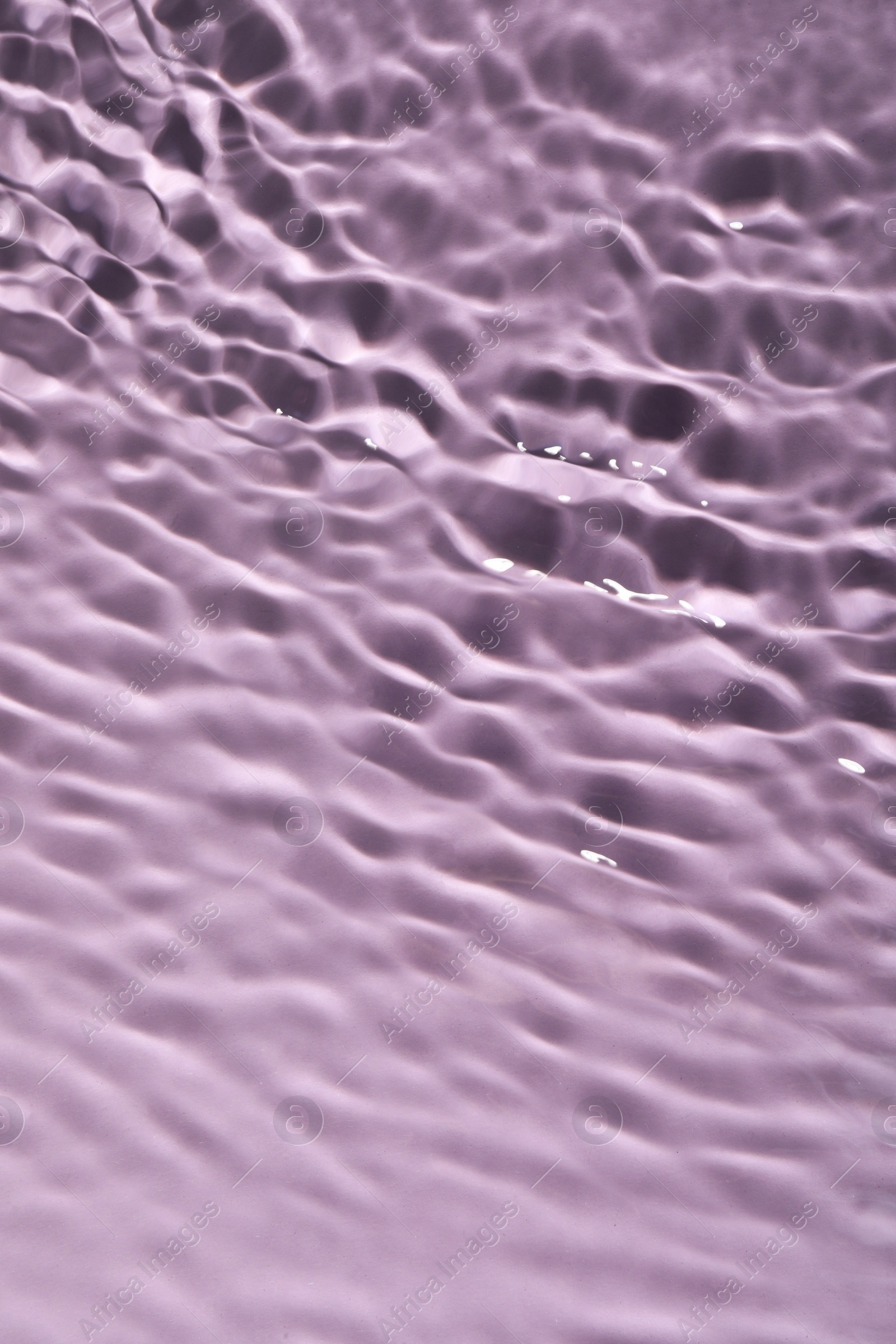 Photo of Closeup view of water with rippled surface on violet background