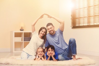 Image of Happy family forming house roof with their hands at home. Insurance concept