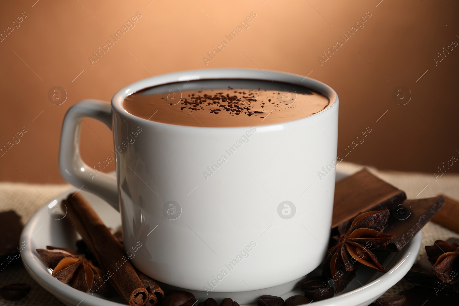 Photo of Cup of delicious hot chocolate, spices and coffee beans on table, closeup