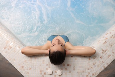 Photo of Beautiful woman relaxing in spa swimming pool, top view