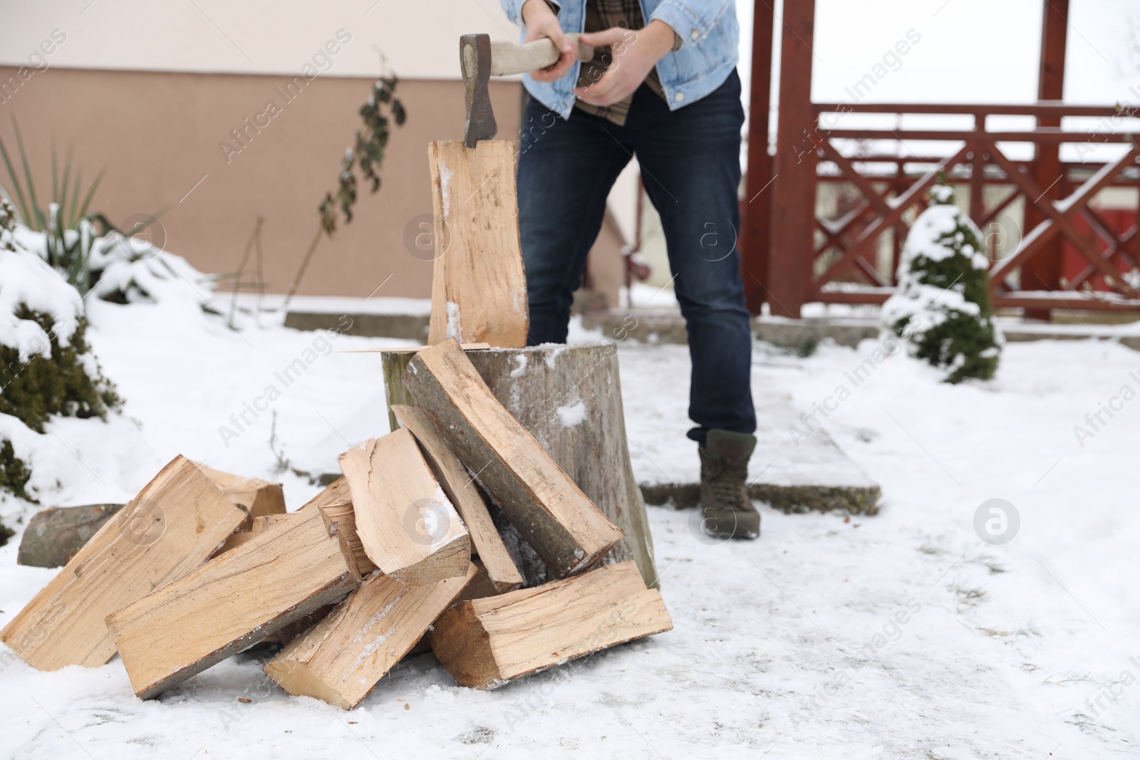 Photo of Man chopping wood with axe outdoors on winter day, closeup