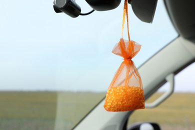 Photo of Air freshener hanging in car against windshield. Space for text