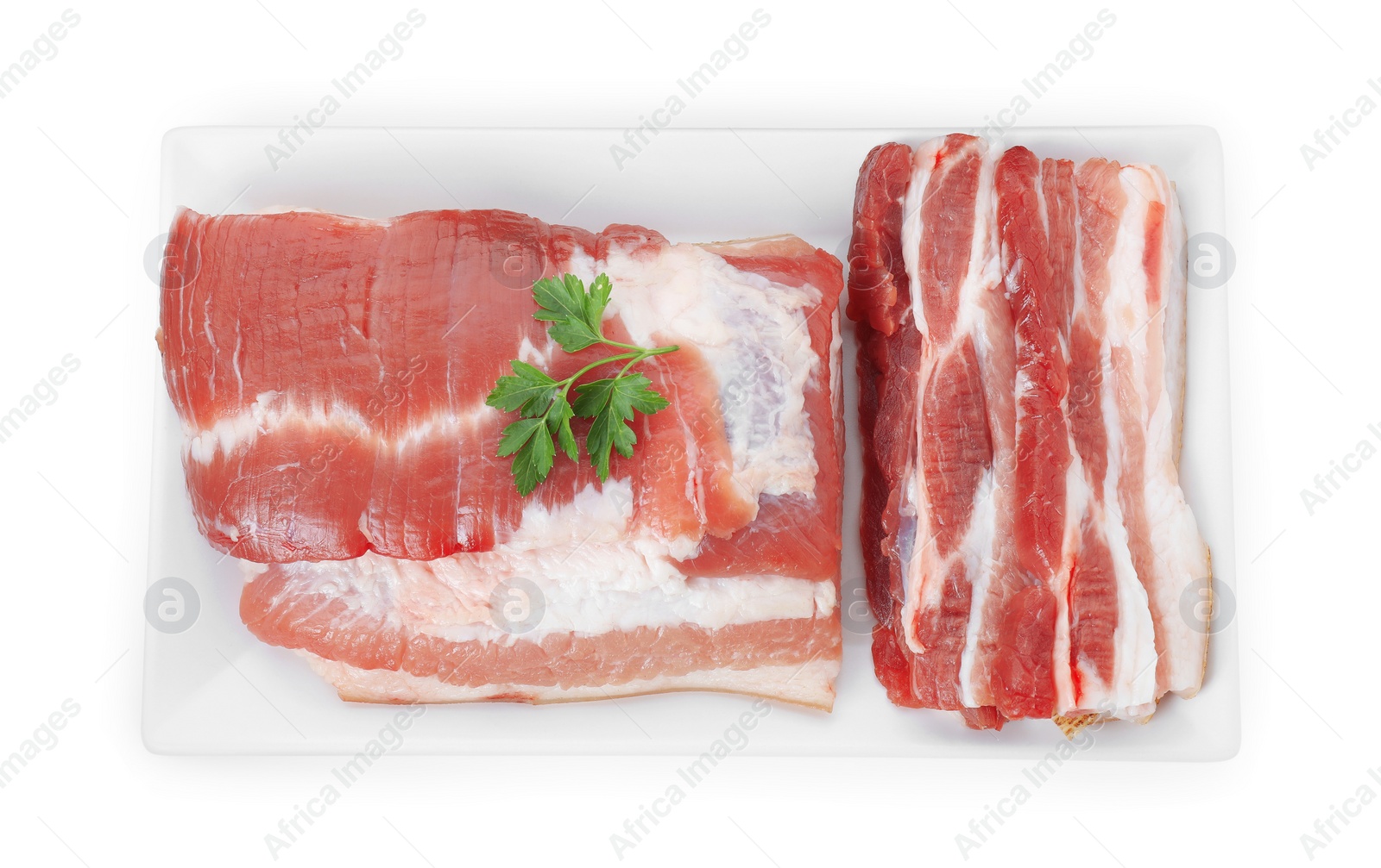 Photo of Pieces of raw pork belly and parsley isolated on white, top view