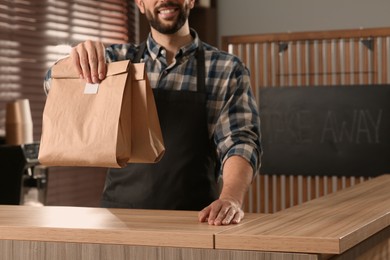 Photo of Worker with paper bags at counter in cafe, closeup