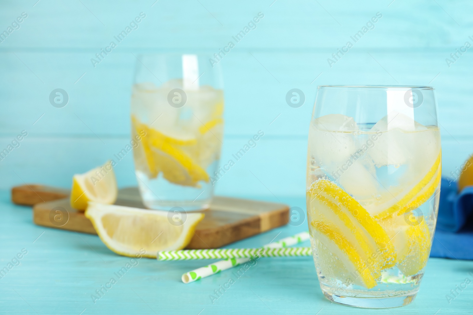 Photo of Soda water with lemon slices and ice cubes on light blue wooden table. Space for text