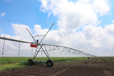 Photo of Modern irrigation system in field under cloudy sky. Agricultural equipment