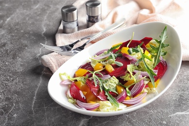 Photo of Bowl with tasty beets salad on gray table