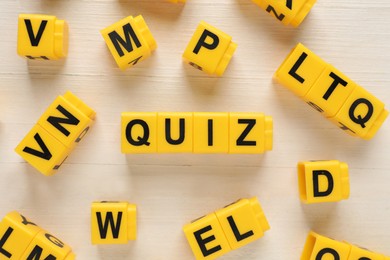 Photo of Yellow cubes with word Quiz on white wooden table, flat lay
