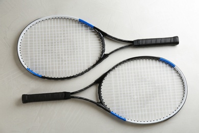 Tennis rackets on grey table, flat lay. Sports equipment
