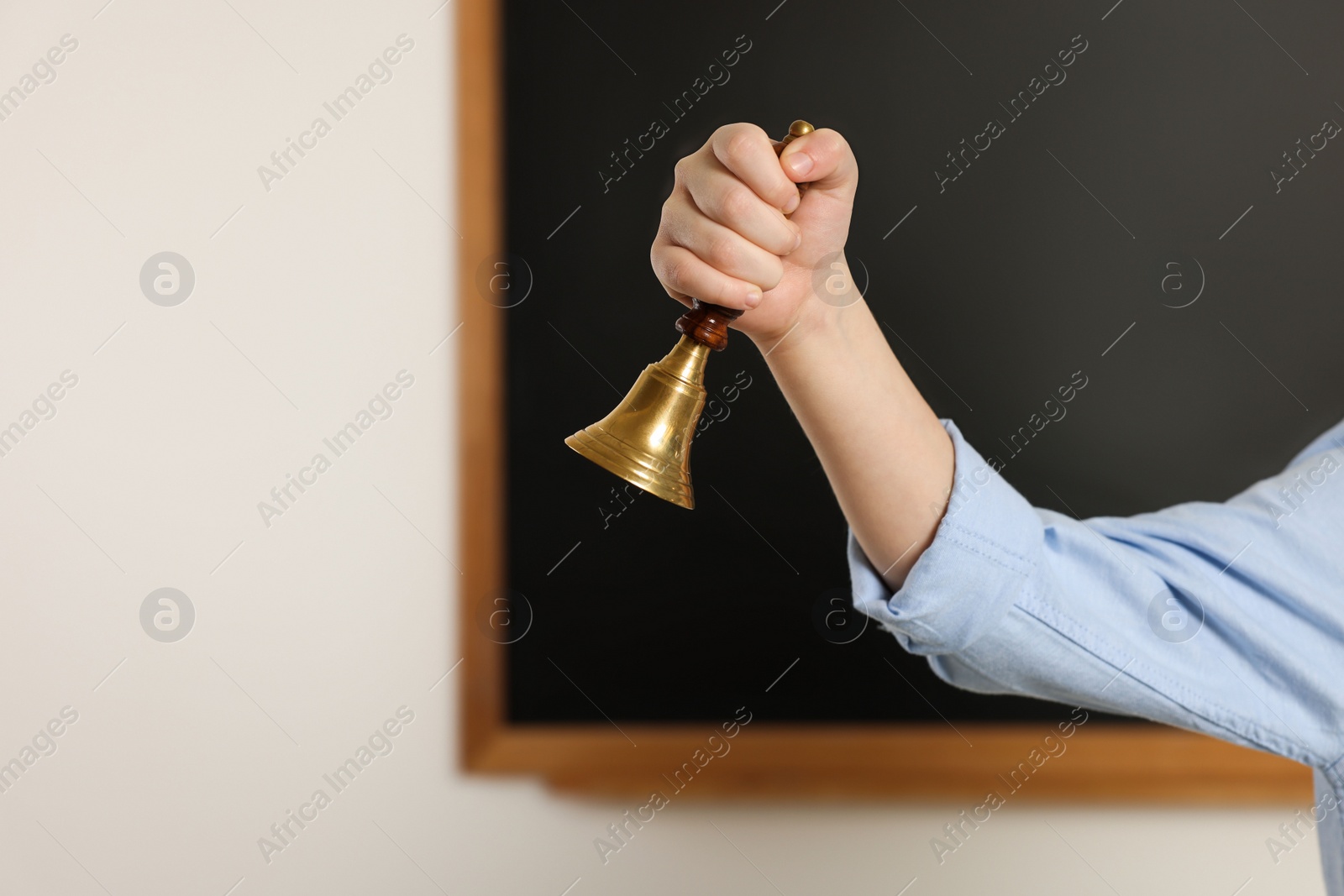 Photo of Boy ringing school bell in classroom, closeup. Space for text