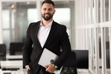 Portrait of smiling man with laptop in office. Lawyer, businessman, accountant or manager